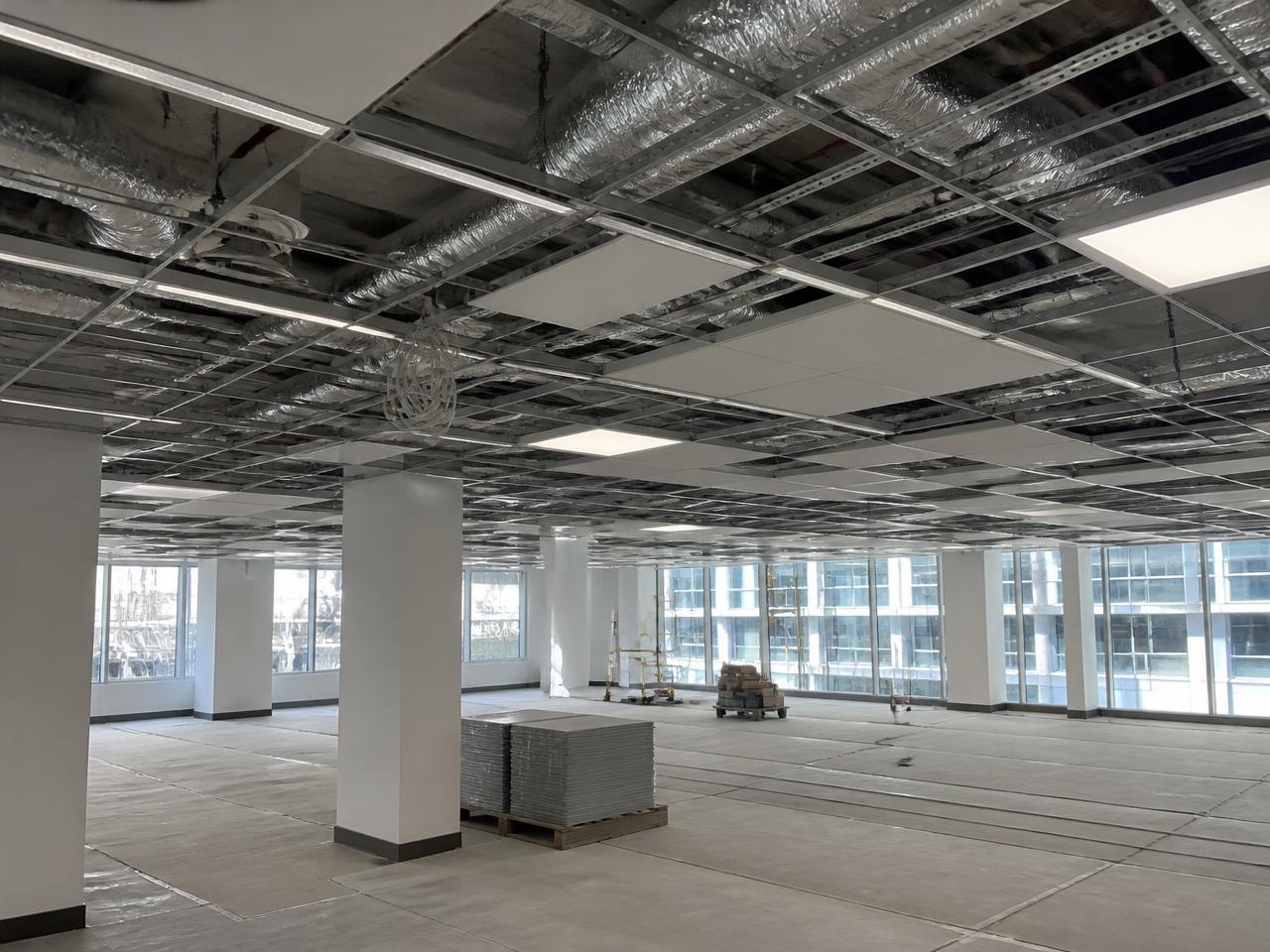 Commercial office floor during technical fit-out with ventilation ducts, cable trays and lighting